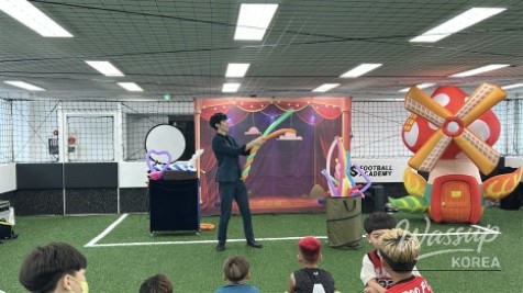 Happy child receiving a large heart-shaped balloon from the magician