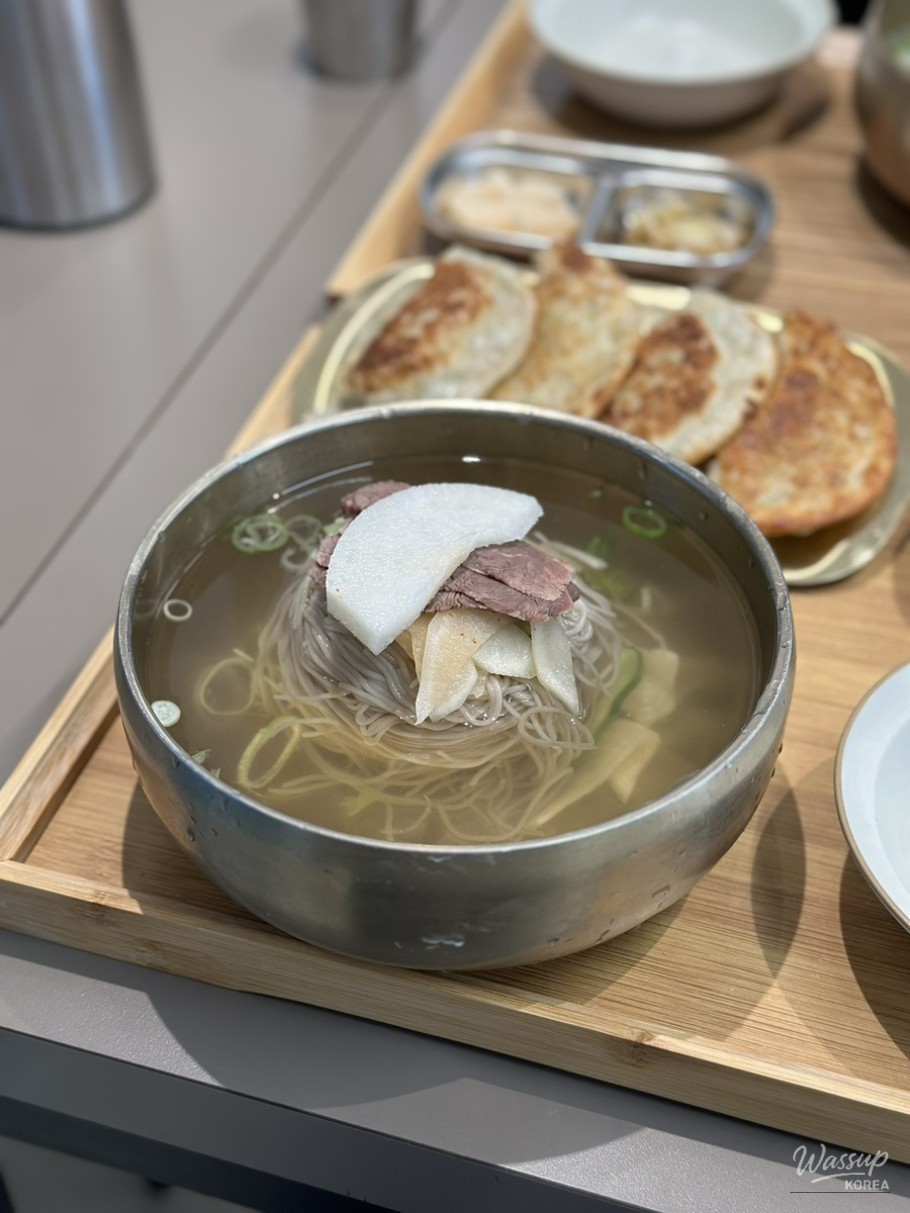 Close-up texture of buckwheat noodles in a clear Pyongyang-style cold broth