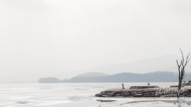 Serene view of Dumulmeori river bank with a traditional wooden boat at dawn