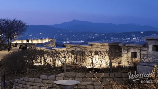 Night view of the Seoul city wall at Naksan Park glowing under winter lights and snow