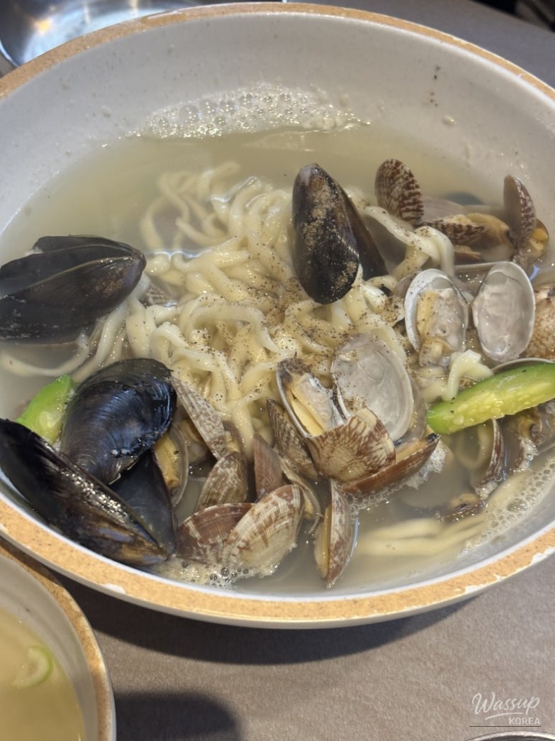 Close-up of the chewy water gun clams in a steaming bowl of kalguksu