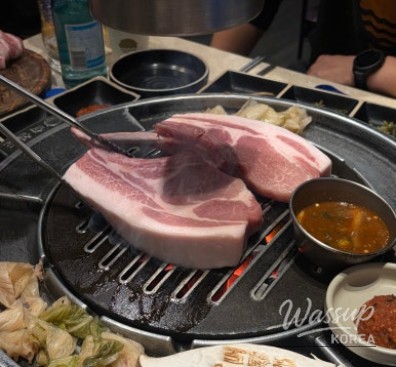 Artfully sliced aged pork served with various dipping sauces and grilled white kimchi