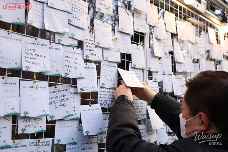 A family writing their New Year wishes on a colorful balloon at a city park event
