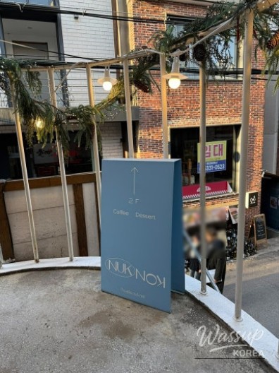 Tiramisu cake with cocoa powder, soft cream, and a heart-shaped strawberry topping at Nuknok