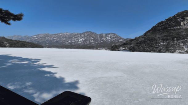 Frozen Sanjeong Lake in Pocheon surrounded by snowy mountains in winter