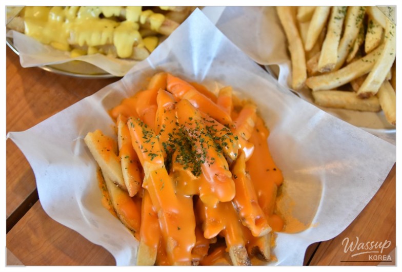 Large handmade burger served in a rustic oak-themed Jeju restaurant setting