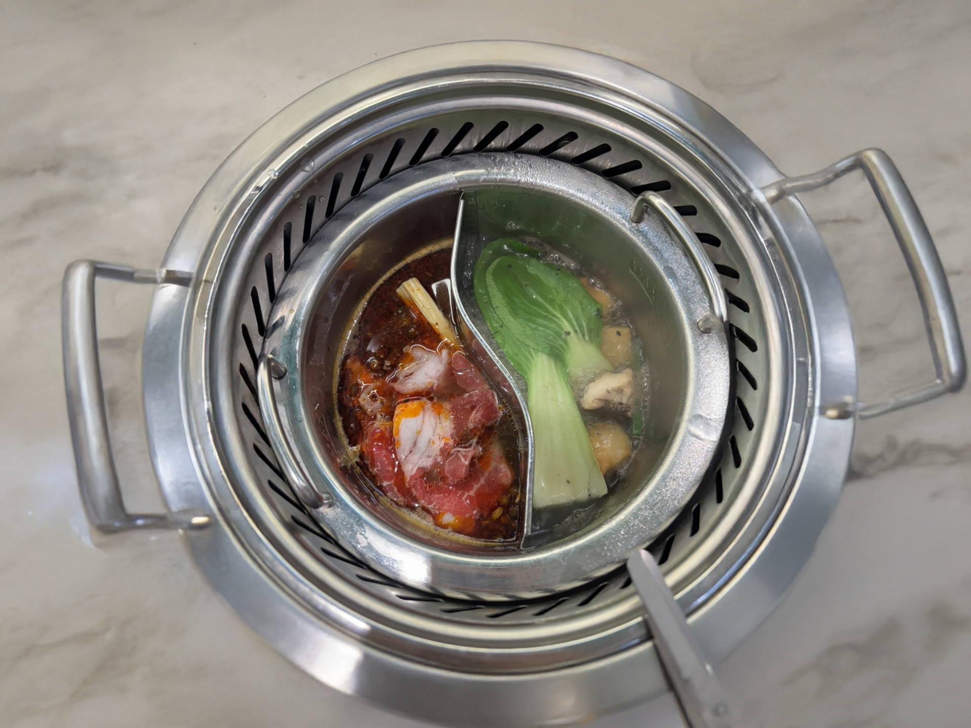 Fresh hot pot ingredients including meat, vegetables, and seafood on the revolving belt