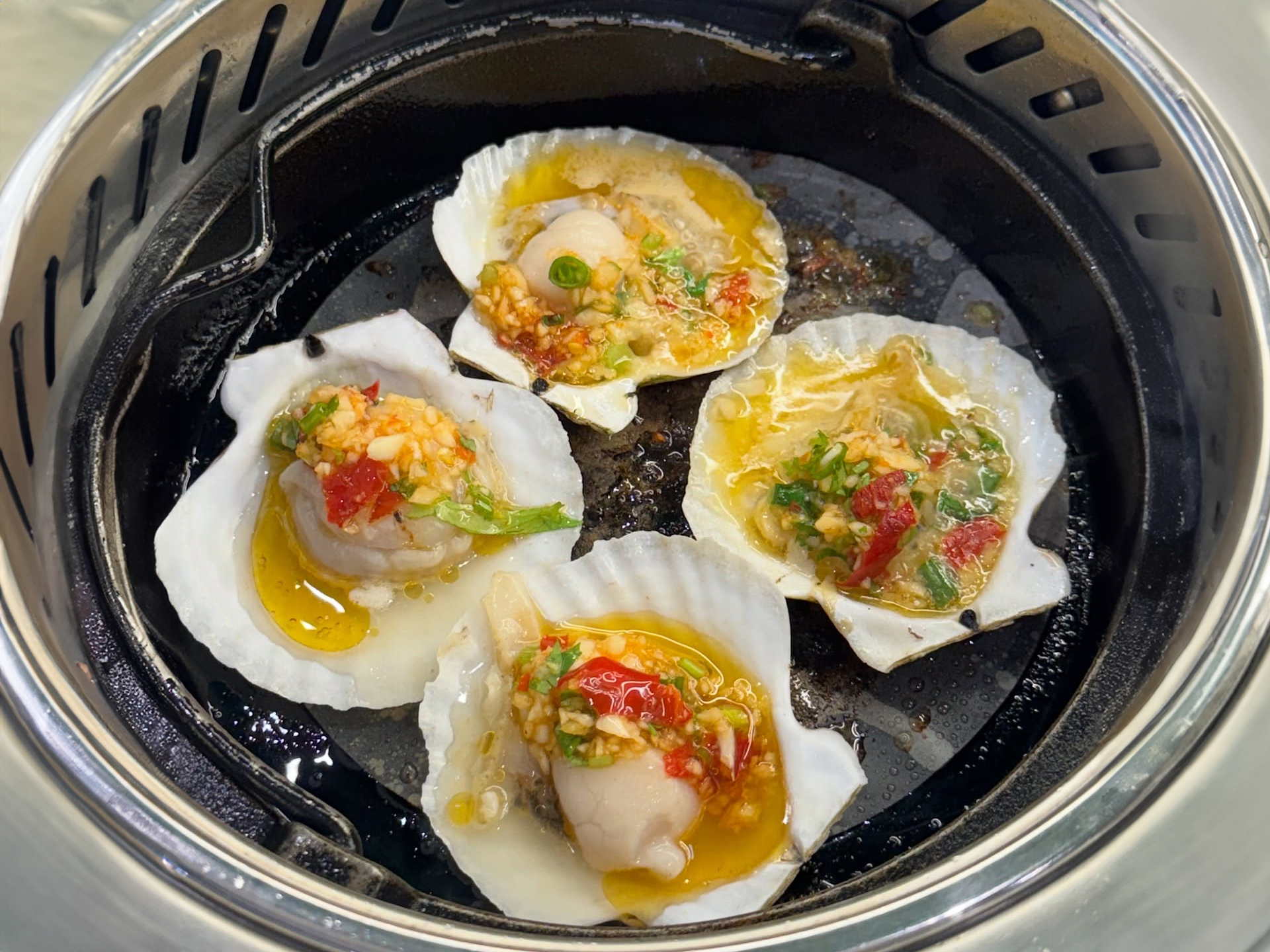 Assorted meats, vegetables, and seafood rotating on rails at a hot pot restaurant