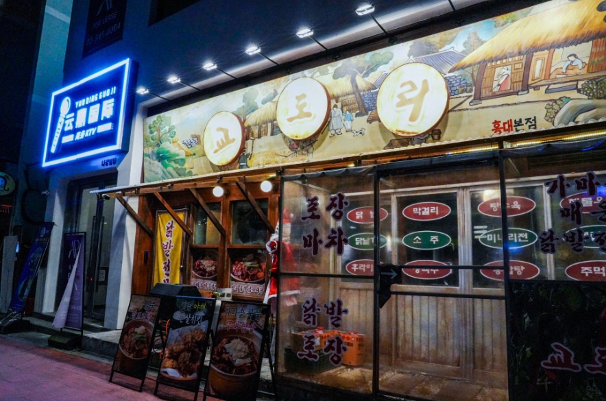 Retro-style exterior of a Korean pocha near Sangsu Station in the evening.