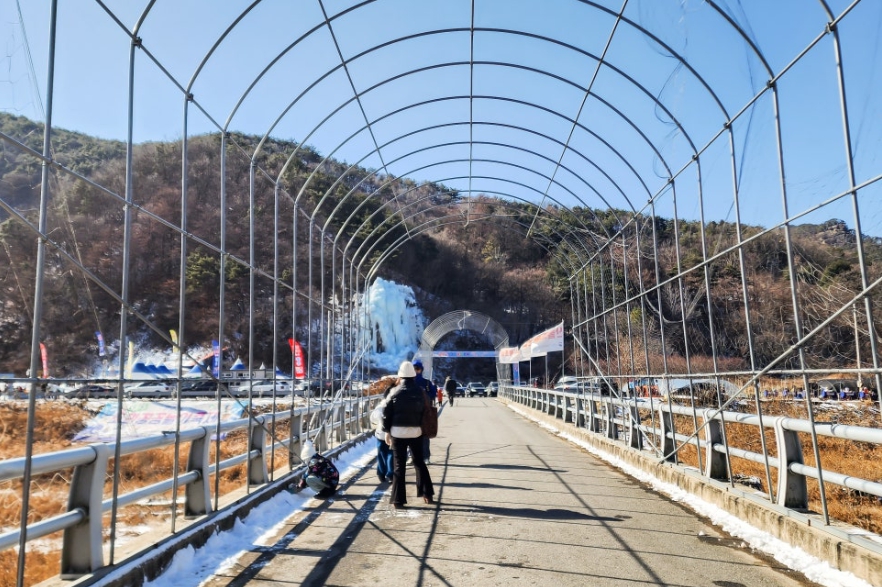 Visitors walking toward the festival area across a village bridge in winter.